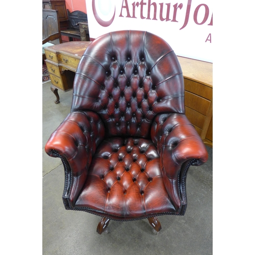 60 - A mahogany and oxblood red leather revolving armchair