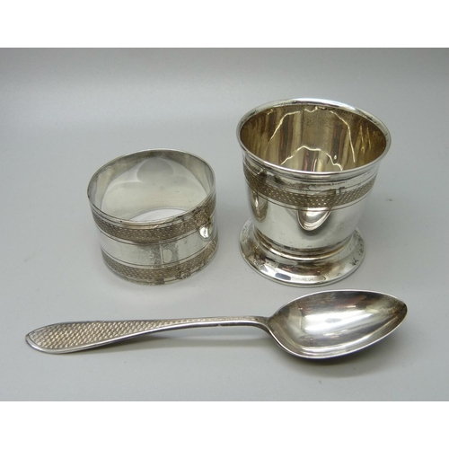 873 - A silver spoon, egg cup and napkin ring, 71g, cased