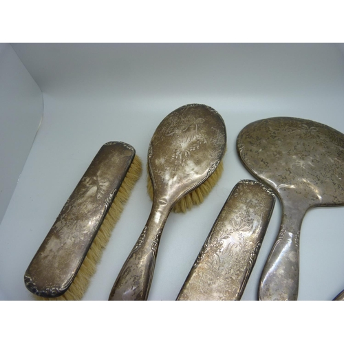 906 - Four silver backed brushes and a silver backed mirror