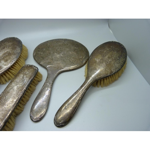 906 - Four silver backed brushes and a silver backed mirror