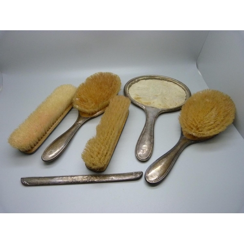 906 - Four silver backed brushes and a silver backed mirror