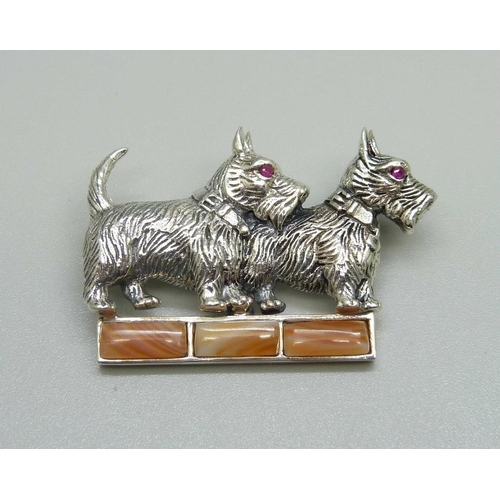 941 - A silver dog brooch with ruby eyes and set with agate, one agate loose