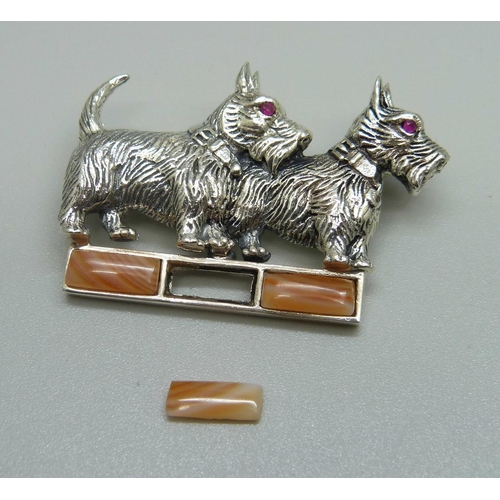 941 - A silver dog brooch with ruby eyes and set with agate, one agate loose