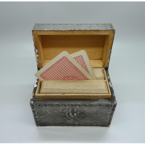 875 - An Arts and Crafts metal covered playing card box, containing two packs of playing cards