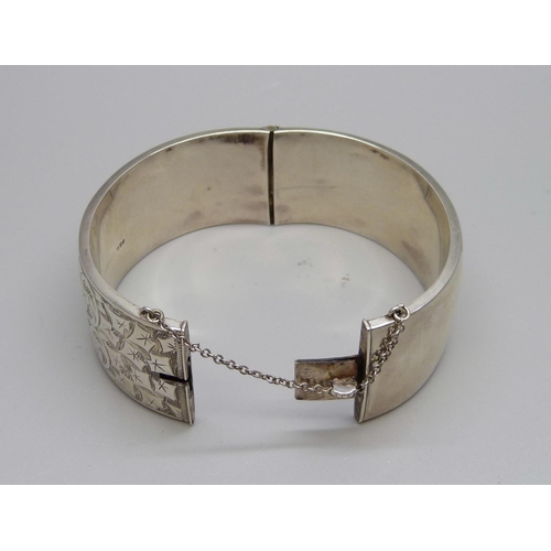 1019 - A wide hallmarked silver bangle with engraved decoration, 34g