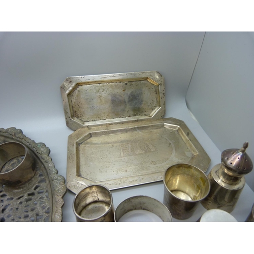 833 - A collection of white metal items; two small trays, fourteen napkin rings, three piece condiment, si... 