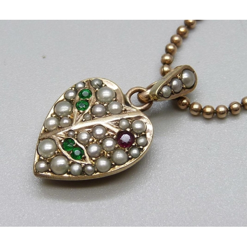 867 - A yellow metal heart shaped pendant set with pearls, green and red stones on a 9ct gold bead  chain,... 