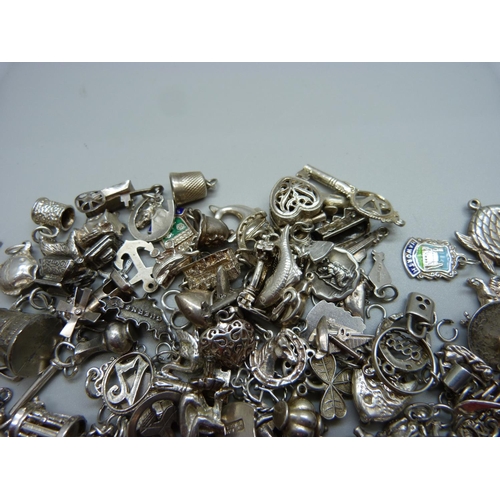 943 - A collection of silver and white metal charms, 235g