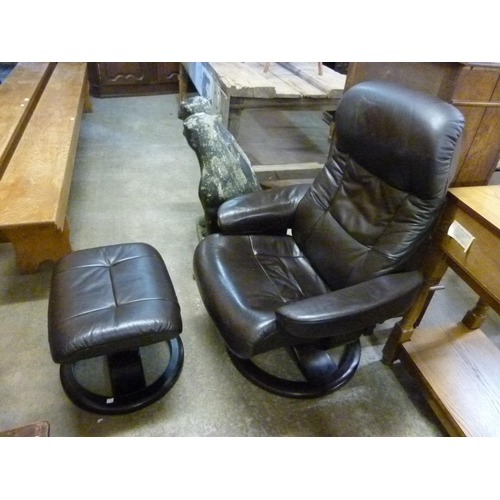 49C - A black leather revolving lounge chair and stool