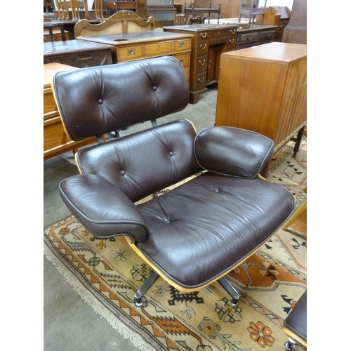 94 - A Charles & Ray Eames style simulated rosewood and brown leather revolving lounge chair and ottoman