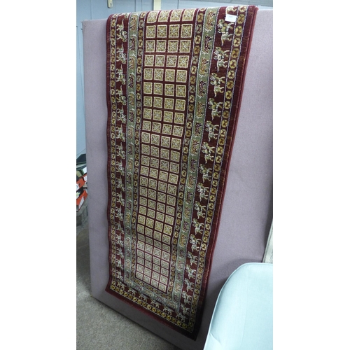 1444 - A claret ground full wool pile runner, with bespoke design depicting animals, 240cm x 70cm