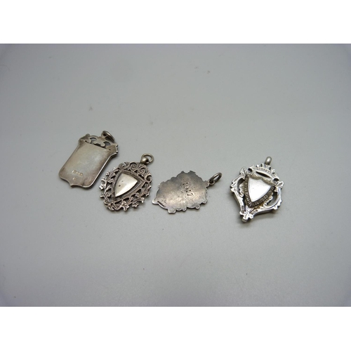 1061 - Four silver fobs, two with applied gold fronts, 58g