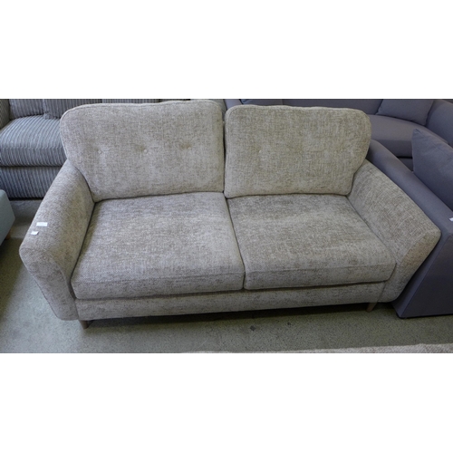 1610 - An oatmeal upholstered convertible three seater sofa/chaise