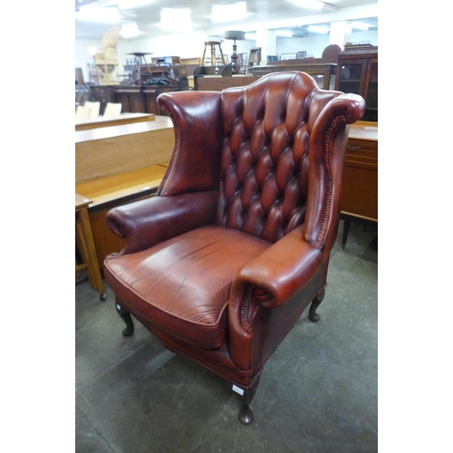 107 - An oxblood leather Chesterfield wingback armchair