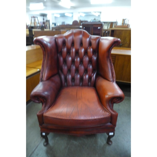 107 - An oxblood leather Chesterfield wingback armchair