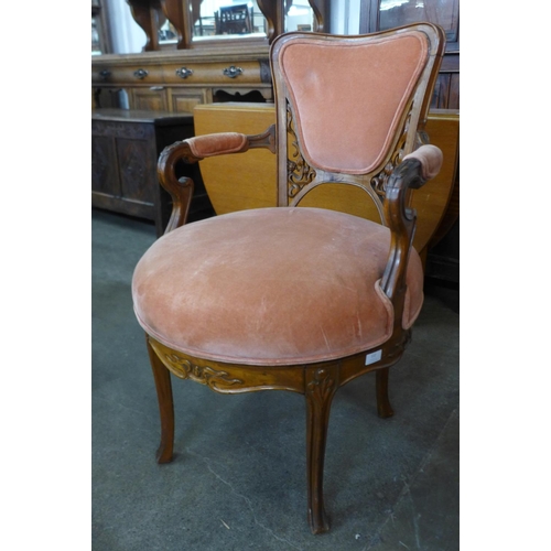 112 - A French Art Nouveau carved walnut and peach fabric upholstered revolving armchair