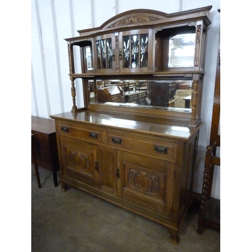 134 - An Arts and Crafts carved oak mirrorback sideboard