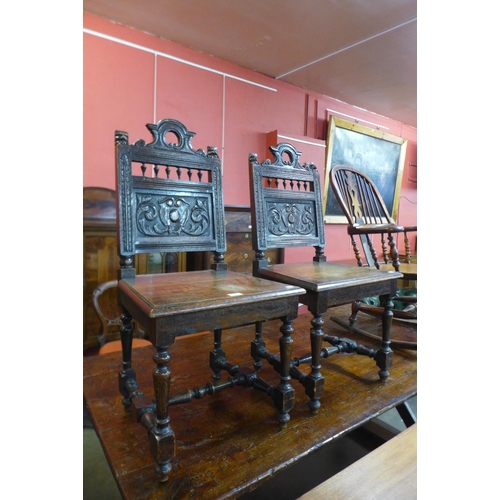 149 - A pair of Victorian Jacobean Revival carved oak hall chairs