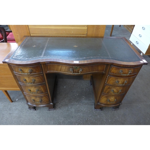 132 - A mahogany and green leather topped serpentine desk