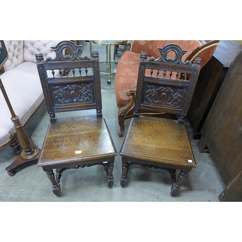 149 - A pair of Victorian Jacobean Revival carved oak hall chairs