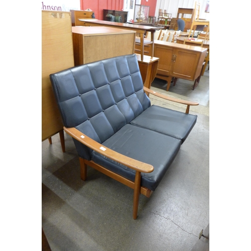 64 - A teak and black vinyl settee