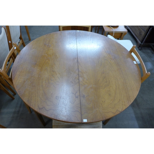 69 - A circular teak extending dining table and five chairs