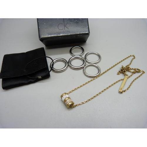 1133 - A Michael Kors necklace and five Calvin Klein rings