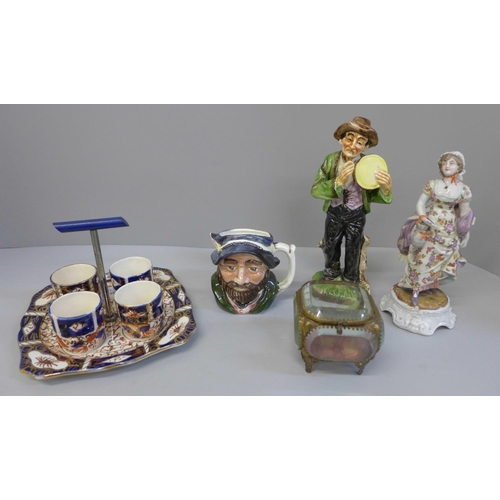 689 - A continental hand painted figure, glass casket, egg cups and stand, etc.