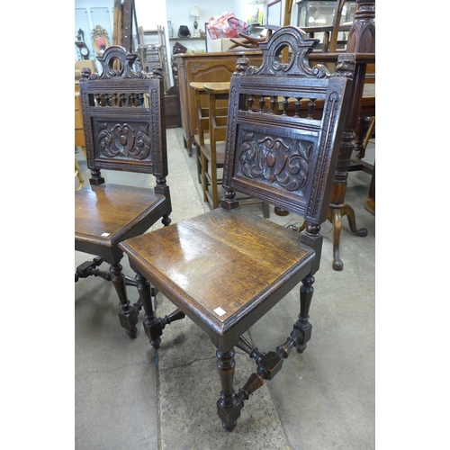 135 - A pair of Victorian Jacobean Revival carved oak hall chairs