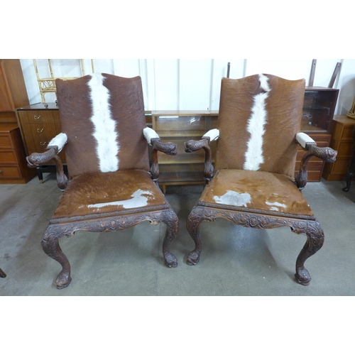 31 - A pair of American Chippendale style carved mahogany and cow hide armchairs (one a/f)