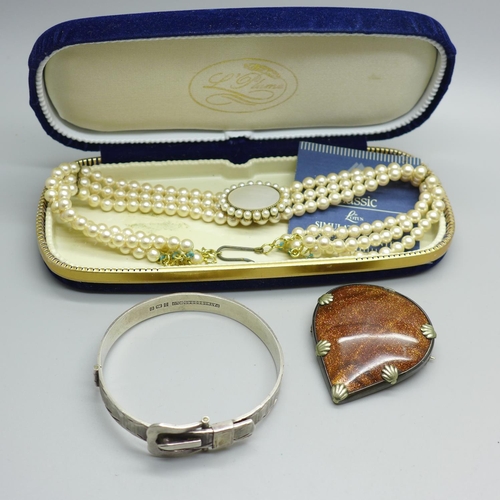 865 - A silver buckle bangle, a goldstone pendant and a simulated pearl necklace