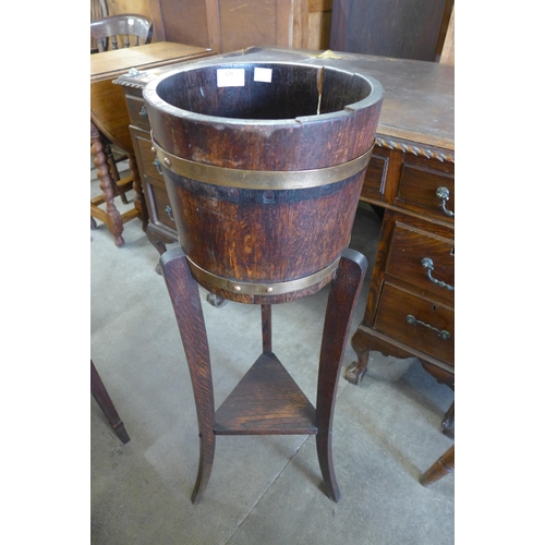 129 - An early 20th Century oak and brass bound barrel shaped jardiniere on stand