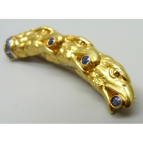 1027 - A high carat yellow metal brooch, three eagles heads set with sapphires, 12.9g