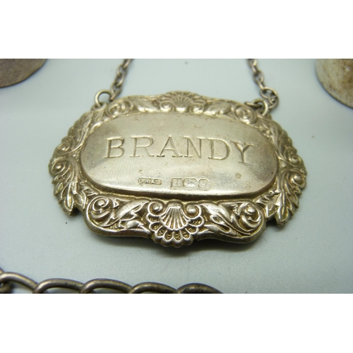 1058 - A silver brandy label, a silver Albert chain with base metal dog clip and T bar, and two white metal... 