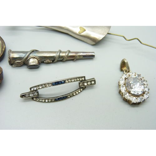 1061 - A silver pendant, a silver brooch, lacking pin, a white metal cheroot holder and a white metal lapel... 