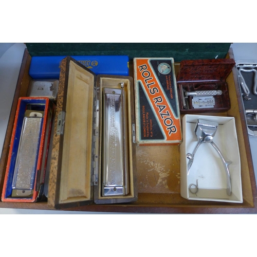 670 - A case containing Rolls razors and three harmonicas, includes Hohner 64 Chromonica