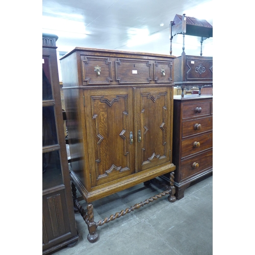 104 - An early 20th Century oak geometric moulded cupboard on barleytwist stand