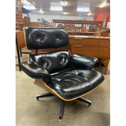 34 - A Ray & Charles Eames style simulated rosewood and black leather revolving lounge chair and ottoman