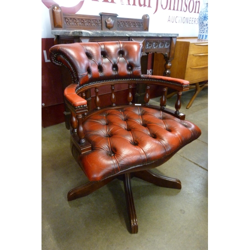 105 - A mahogany and oxblood red leather revolving Captains desk chair