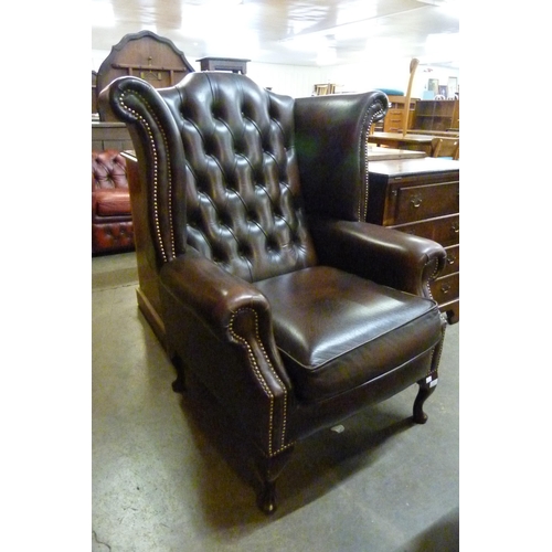 114 - A chestnut brown leather Chesterfield wingback chair