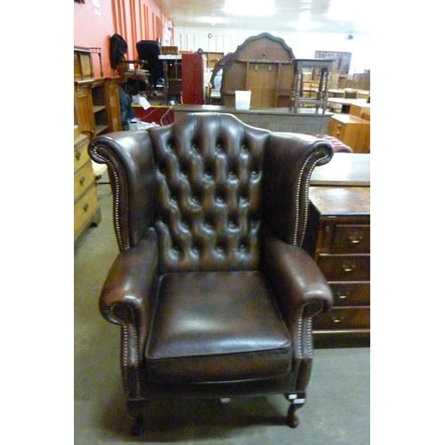 114 - A chestnut brown leather Chesterfield wingback chair