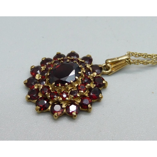 1047 - A yellow metal and garnet pendant on a 9ct gold chain, chain 1.8g