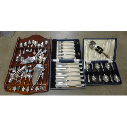 1205 - A collection of plated cutlery and collectors spoons on display rack **PLEASE NOTE THIS LOT IS NOT E... 