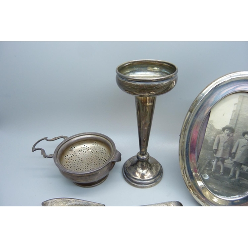 893 - A silver tea strainer and holder, three silver napkin rings, a silver butter knife, a silver mustard... 