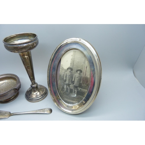 893 - A silver tea strainer and holder, three silver napkin rings, a silver butter knife, a silver mustard... 