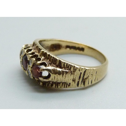 1075 - A 1970's 9ct gold and garnet trilogy ring with bark effect, 3.3g, M