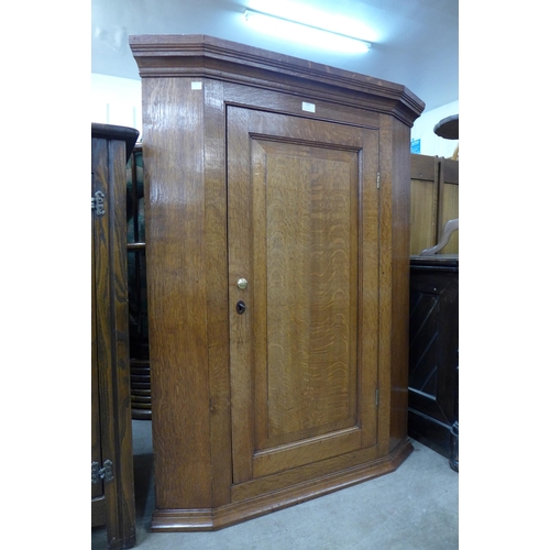 153 - A George III oak splay front wall hanging corner cupboard