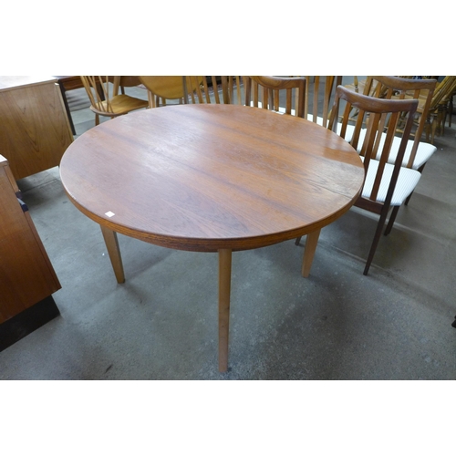 31 - A circular teak extending dining table