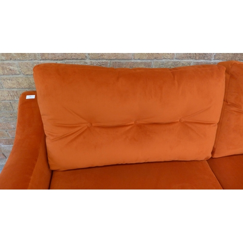 20 - A tangerine velvet buttoned back three seater sofa and footstool (H=90cm x W=187cm x D=90cm)