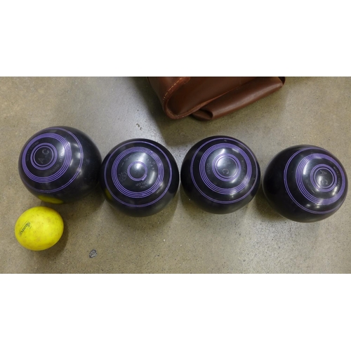 1132 - A set of four lawn bowls and a jack in a leather case